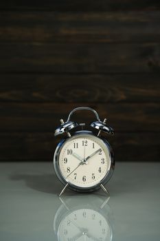 Retro alarm clock on table near wood background