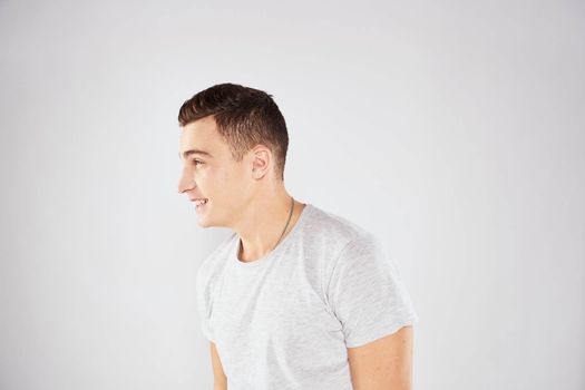 Man in a white t-shirt emotions gestures with hands close-up cropped view light background. High quality photo