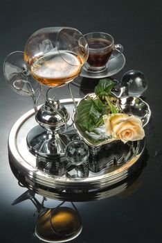 Cup of coffee and glass of cognac on a glass background