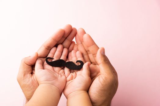 Father and his son kid uses hand holding black mustache, studio shot isolated on white background, Prostate cancer awareness month, Fathers day, minimal November moustache concept