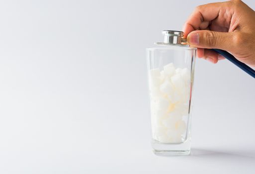 Hand of doctor hold stethoscope check on glass full of white sugar cube sweet food ingredient, isolated on white background, health high blood risk of diabetes and calorie intake unhealthy drink