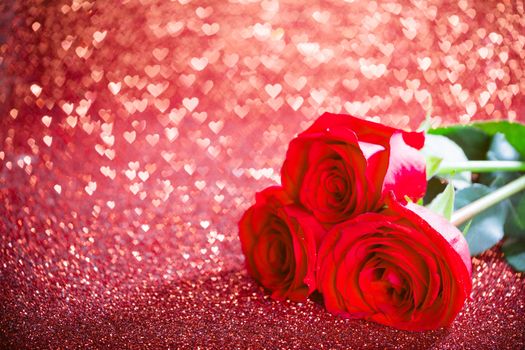 Three red roses and over hearts bokeh glittering background