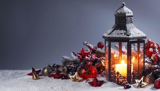 Christmas composition of lantern colorful ornaments balls stars candles and fir tree branches on snow