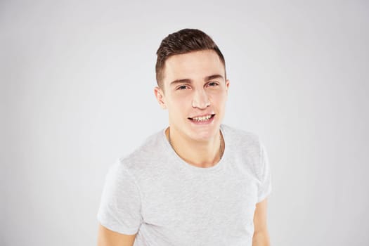 Man in a white t-shirt emotions gestures with hands close-up cropped view light background. High quality photo