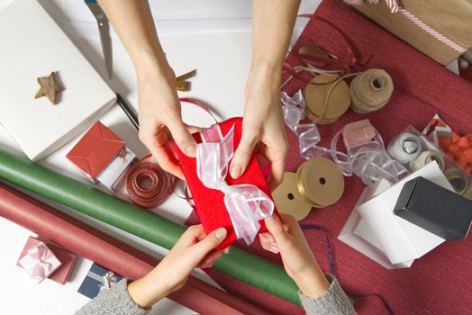 Close Up on hands women hands holding and giving red gift box with white ribbon to girl. Birthday, Christmas, Mother's day and New year present box.