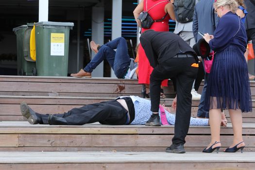 MELBOURNE, AUSTRALIA - NOVEMBER 05, 2019: Drunnk punters at the end of the Lexus Melbourne Cup Day at the 2019 Melbourne Cup Carnival at Flemington Racecourse in Melbourne Australia