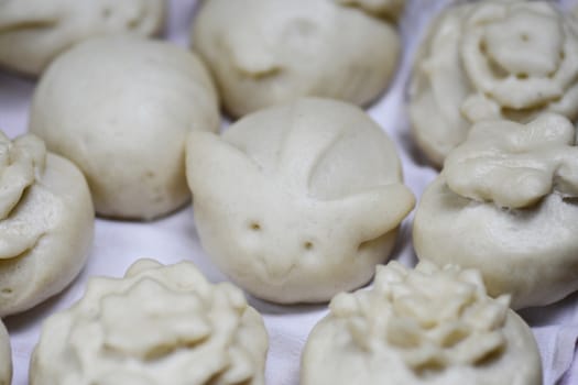 Asian steamed buns in different shapes on a white cloth