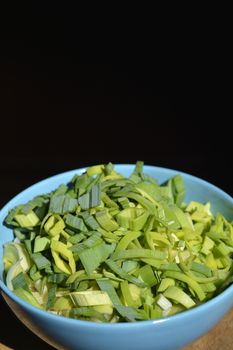 Diced fresh leek leaves in light blue bowl