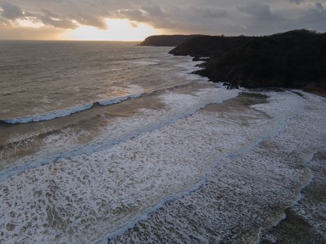 Drone Shot Of A Sunset At Caswell Bay In Gower, Wales, UK. Foamy Seas, With Interesting Colours In The Clouds