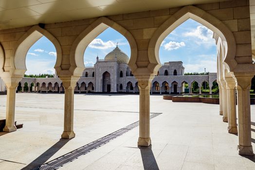 View of the white mosque in the sunset light through the Arches. Bolghar, Russia