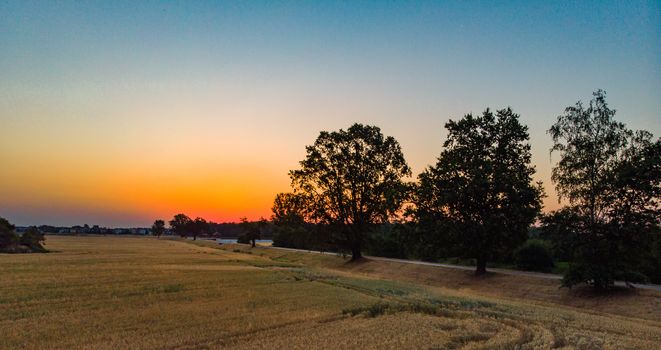 Aerial view to rising sun over field and forest at morning