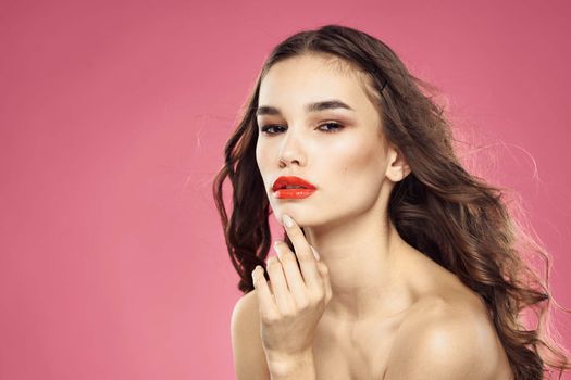 Beautiful woman with red lips on a pink background nude shoulders cropped view. High quality photo