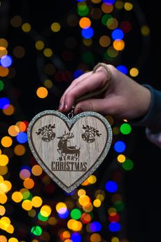 Woman's hands hold christmas decoration. Christmas and New Year holidays background, winter season with Christmas ornaments and blurred lights