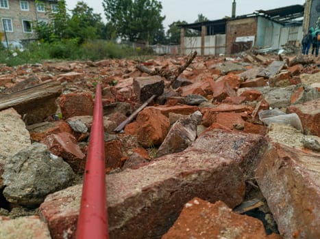 Long red stick lying on pile of stones and old bricks