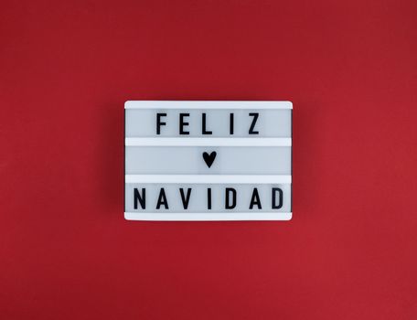 Light box with Feliz Navidad phrase, Spanish Merry Christmas on red background.