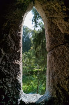 Old stone window view to green landscapes full of trees and bushes