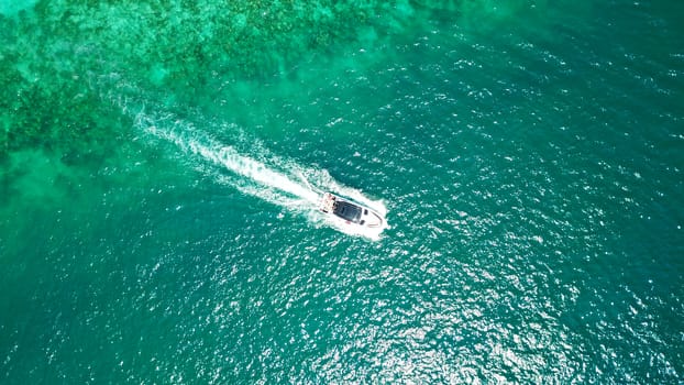 Turquoise clear water. Yachts, boats floating. Water Gradient from light to dark blue. Phi Phi don island, shooting from a drone from the air. White sand, green trees, palm trees and large hills.