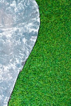 Rough surface texture of gray color concrete pathway brick and green color of plastic artificial grass