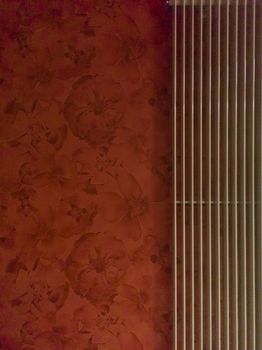 Red wall with floral pattern and pipes of heating system