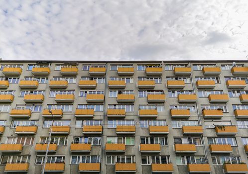 Big block of flats full of yellow balconies at cloudy day