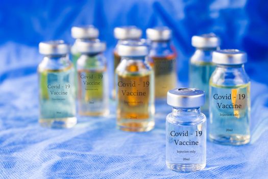 Corona virus and Covid - 19 new vaccine in ampules, different color variations of vaccine on the blue background