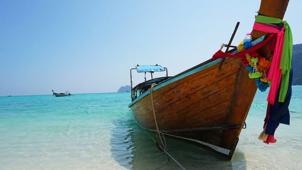 Sea long-tailed boats. Traditional Thai boats. Bright colored ribbons. Turquoise, blue, clear water. White sand on the beach. Holiday boat. A small wave. Travel to Asia. The Island Of Phi Phi Don.