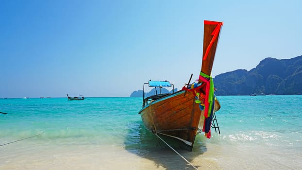 Sea long-tailed boats. Traditional Thai boats. Bright colored ribbons. Turquoise, blue, clear water. White sand on the beach. Holiday boat. A small wave. Travel to Asia. The Island Of Phi Phi Don.