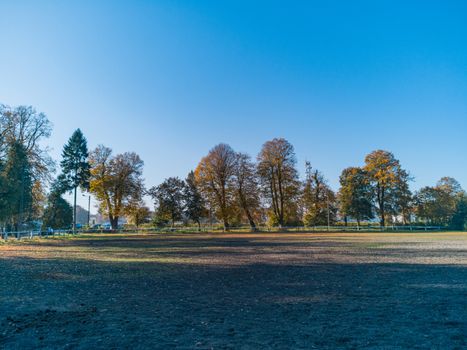 Empty paddock for horses with colorful fall trees around