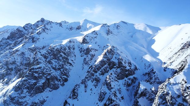 Huge rocks covered with snow. Dangerous terrain. High mountains, cliffs, and large rocks. Shadow from the sun's rays. Top and side view from the drone. An epic place. The Mountains Of Almaty.