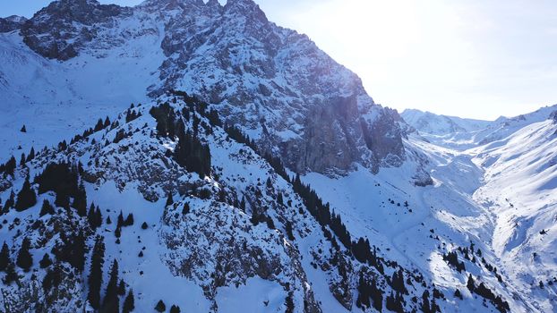 Huge rocks covered with snow. Dangerous terrain. High mountains, cliffs, and large rocks. Shadow from the sun's rays. Top and side view from the drone. An epic place. The Mountains Of Almaty.