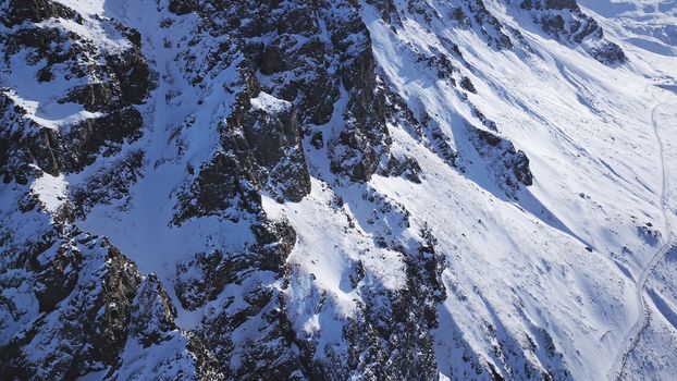 Huge rocks covered with snow. Dangerous terrain. High mountains, cliffs, and large rocks. Shadow from the sun's rays. Top and side view from the drone. An epic place. The Mountains Of Almaty.