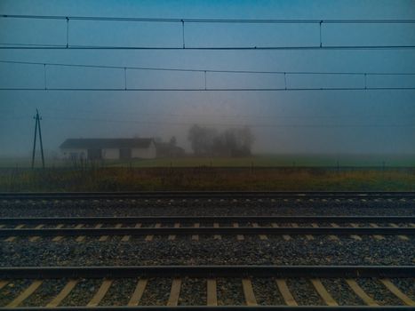 Morning fog over train rails and small barn