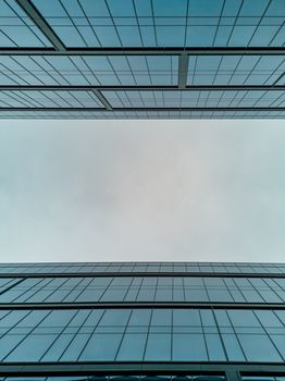 Upward view to two high corporate buildings full of windows