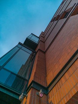 Upward view to modern building with red brick walls and large windows