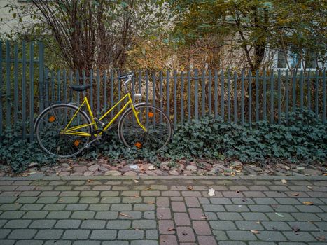 Old yellow bicycle leaning against the metal fence