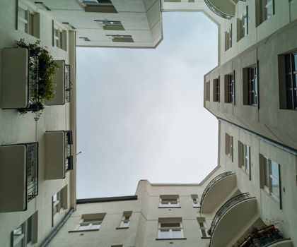 Upward view to building well in small square with old tenement house around