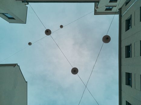 Upward view to modern construction of lamps in square between old tenement houses