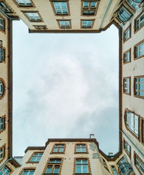 Upward view to building well in small square with old tenement house around