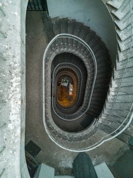 Old concrete spiral staircase with metal railings and lights downstairs