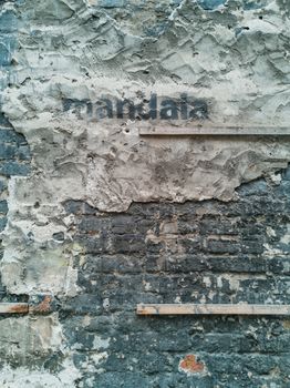 Grunge wall of building with wooden laths cement and sprayed word