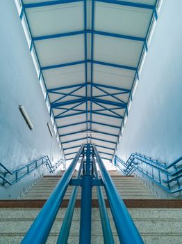 Concrete stairs to train platform with metal roof and blue railings