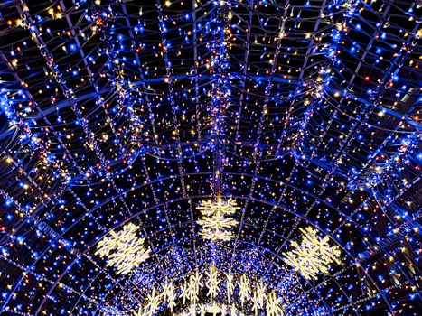 Round colorful christmas tunnel made of christmas lights in city streets