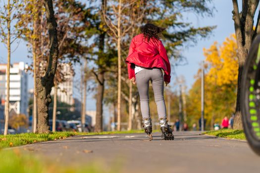 Active leisure. A sportive girl is rollerblading in an autumn park.