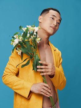 Dreamy man with a bouquet of flowers and a yellow coat, naked torso. High quality photo