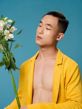 Guy of Asian appearance with a bouquet of white flowers holidays gifts yellow coat. High quality photo