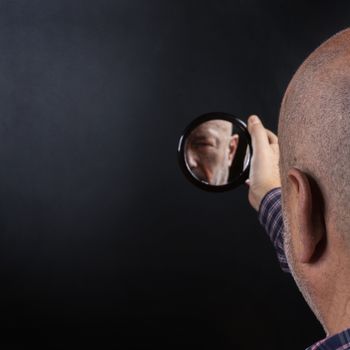 a man is reflected in a small mirror