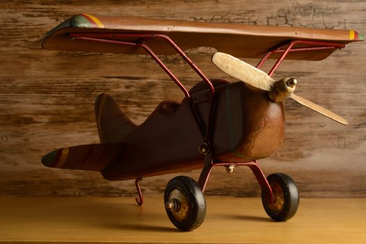 A closeup view of a childs toy wooden airplane resting on a shelf.