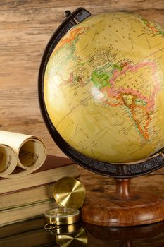 A vertical image of a world globe and paper maps for the avid traveler.