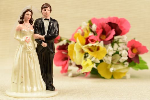 A closeup image of the wedding cake topper and brides bouquet of flowers.