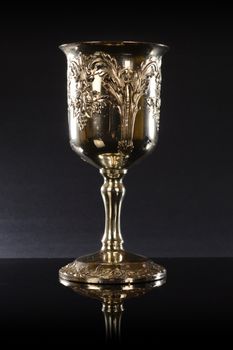 A treasured silver cup over a black reflective background.